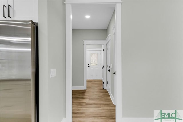 corridor with light wood-style flooring, recessed lighting, and baseboards