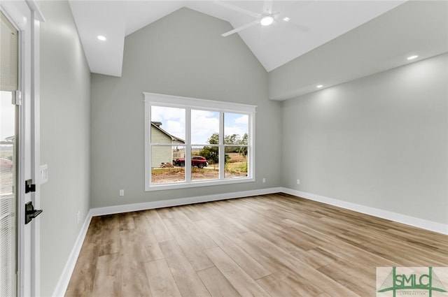 empty room with a ceiling fan, light wood-style floors, baseboards, and high vaulted ceiling