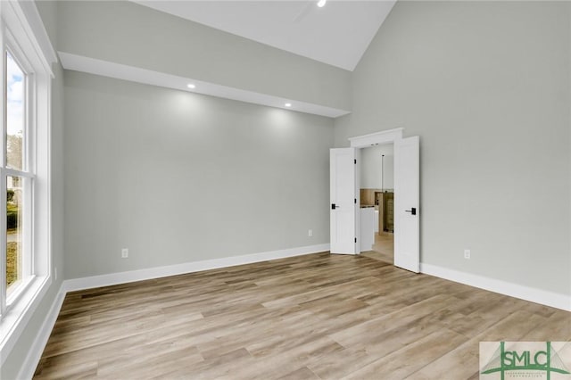 unfurnished room with recessed lighting, baseboards, light wood-style floors, and high vaulted ceiling