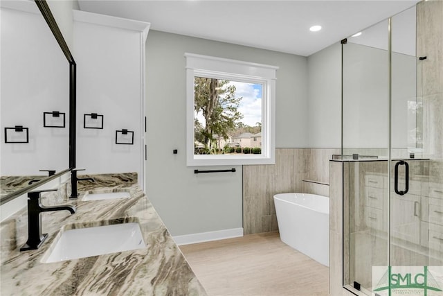 bathroom with a sink, a freestanding tub, a stall shower, and double vanity