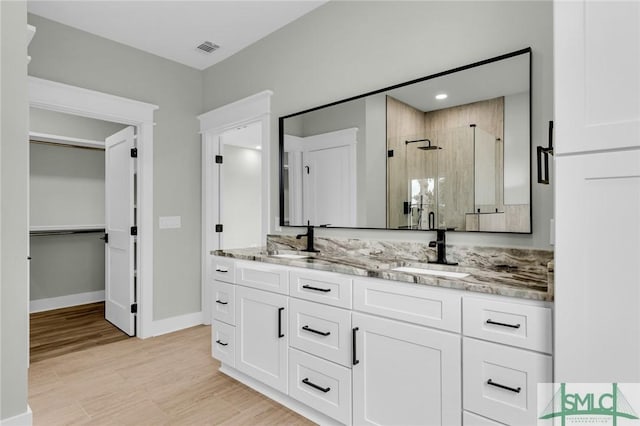 full bathroom featuring double vanity, visible vents, a stall shower, and a sink