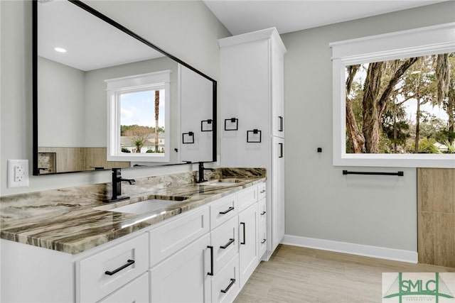 bathroom with double vanity, baseboards, and a sink