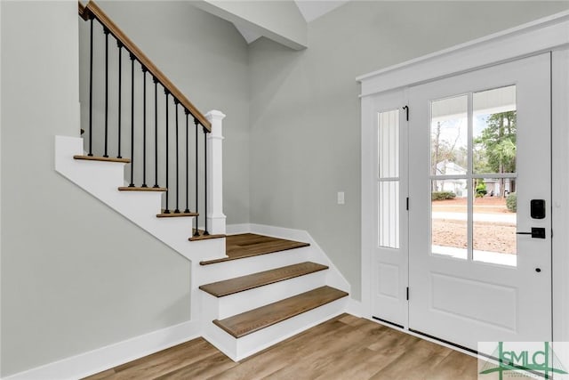 foyer entrance with stairway, baseboards, and wood finished floors