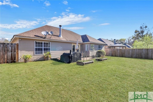 rear view of property featuring a fenced backyard, a yard, and a vegetable garden