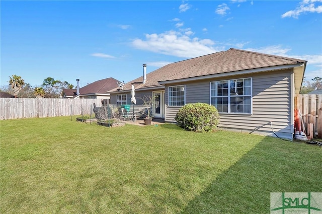back of property featuring a lawn, a fenced backyard, and a shingled roof