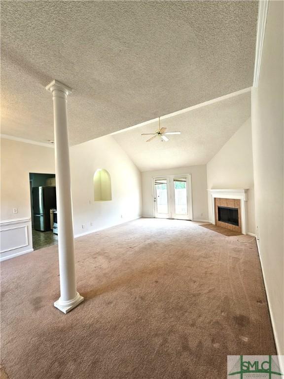 unfurnished living room featuring lofted ceiling, a textured ceiling, ceiling fan, carpet flooring, and a tile fireplace