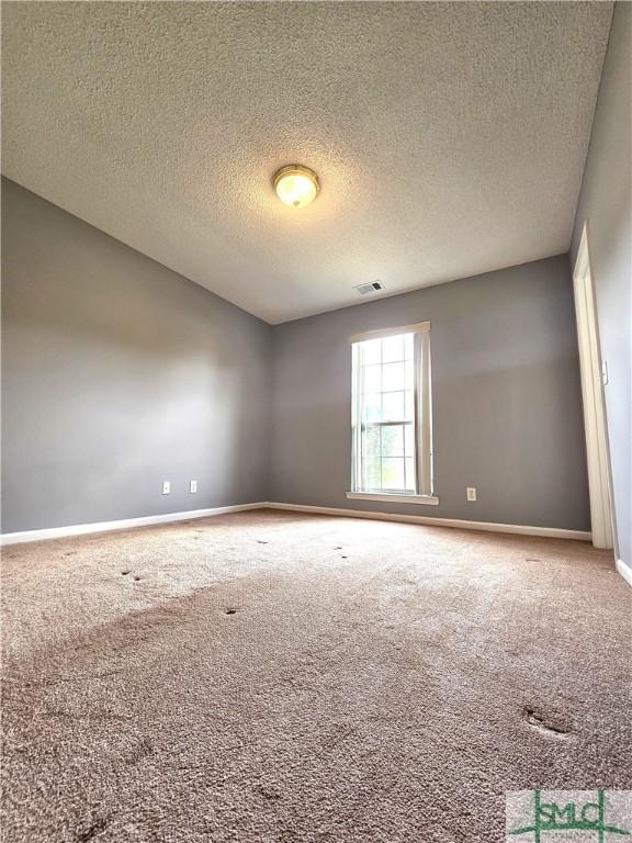 empty room with baseboards, a textured ceiling, visible vents, and carpet