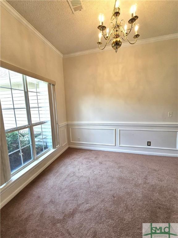 spare room featuring a chandelier, a textured ceiling, visible vents, and ornamental molding