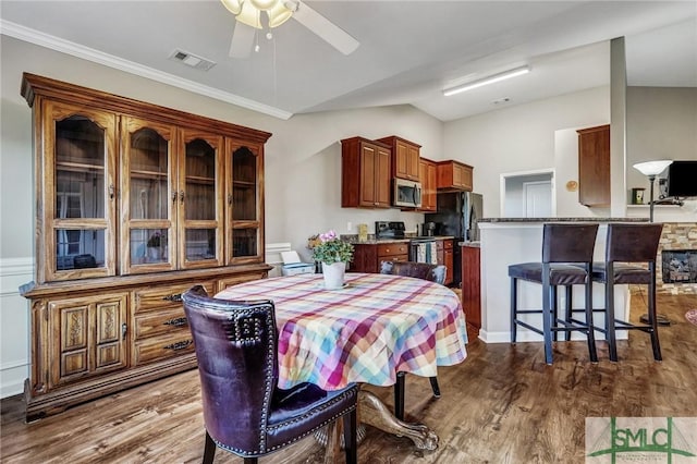 dining area featuring visible vents, crown molding, ceiling fan, dark wood finished floors, and vaulted ceiling