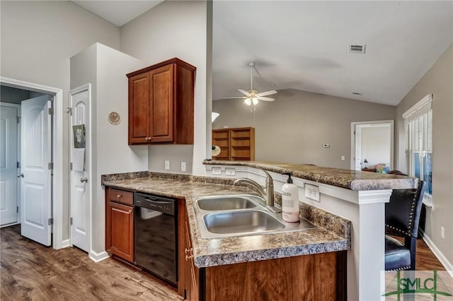 kitchen with a sink, wood finished floors, a peninsula, dishwasher, and vaulted ceiling