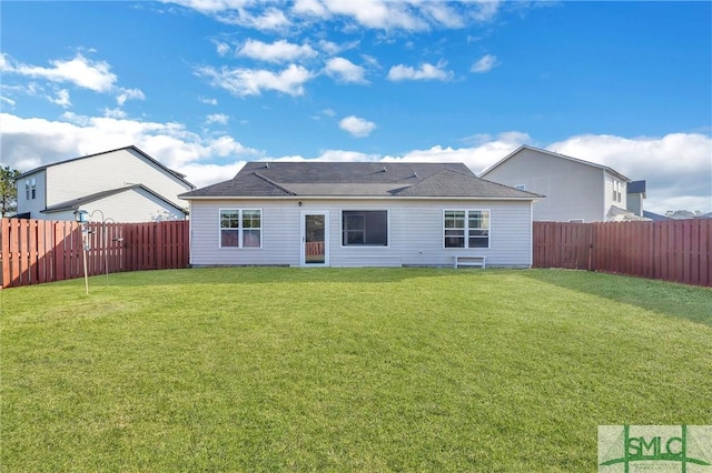 rear view of house with a yard and a fenced backyard