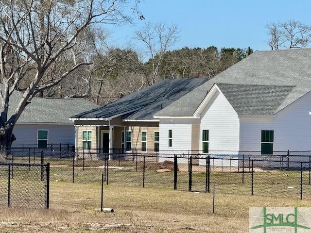 rear view of property with a yard, fence, and a shingled roof