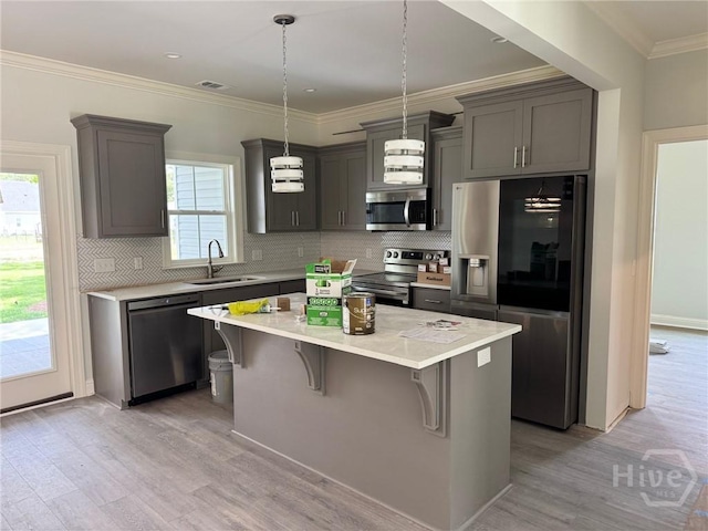 109 Ennis Rd, Pembroke, GA 31321 - kitchen featuring stainless steel appliances, light wood-style floors, a kitchen breakfast bar, a center island, and crown molding