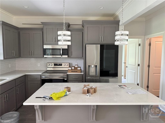 109 Ennis Rd, Pembroke, GA 31321 - kitchen featuring appliances with stainless steel finishes, gray cabinetry, a kitchen bar, ornamental molding, and a center island