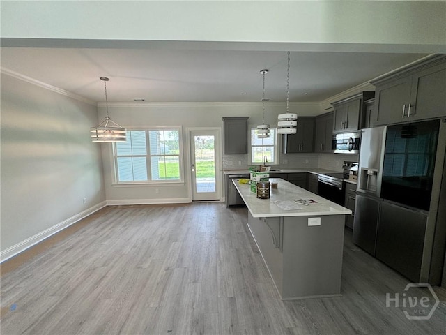 109 Ennis Rd, Pembroke, GA 31321 - kitchen with stainless steel appliances, a kitchen island, light countertops, light wood-style floors, and pendant lighting