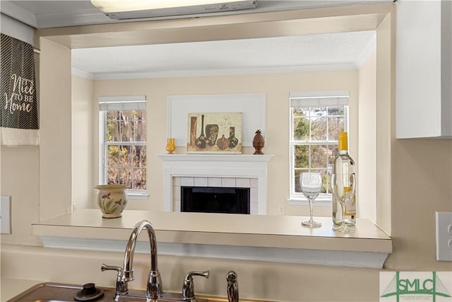 bar featuring a tiled fireplace, a sink, and ornamental molding