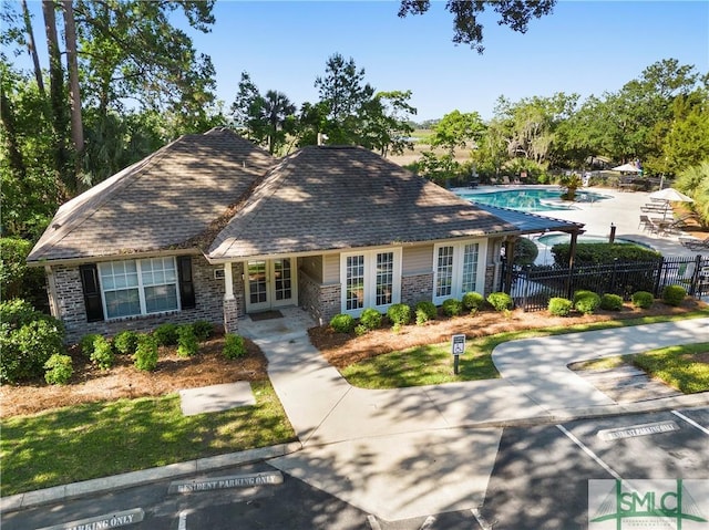 view of front of house with a fenced in pool, fence, french doors, a patio area, and brick siding