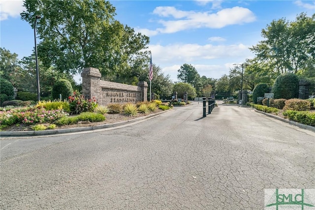 view of street with street lights, a gate, curbs, and a gated entry