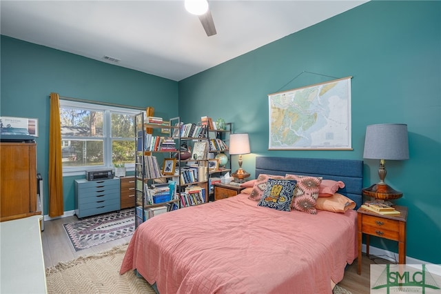 bedroom with ceiling fan, wood finished floors, visible vents, and baseboards