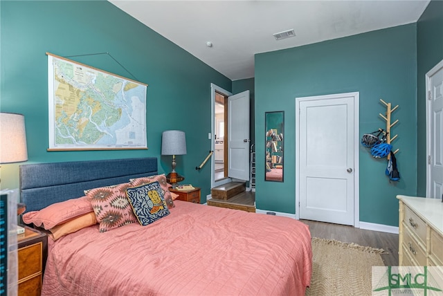 bedroom featuring visible vents, baseboards, and wood finished floors