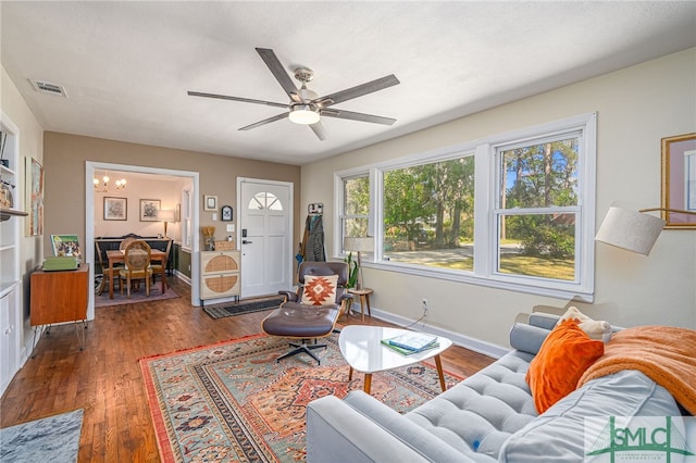 living area with visible vents, ceiling fan with notable chandelier, baseboards, and wood-type flooring