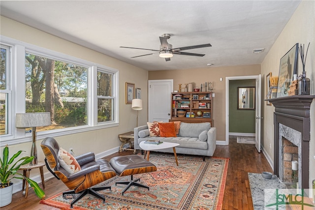 living room featuring visible vents, wood finished floors, baseboards, and ceiling fan