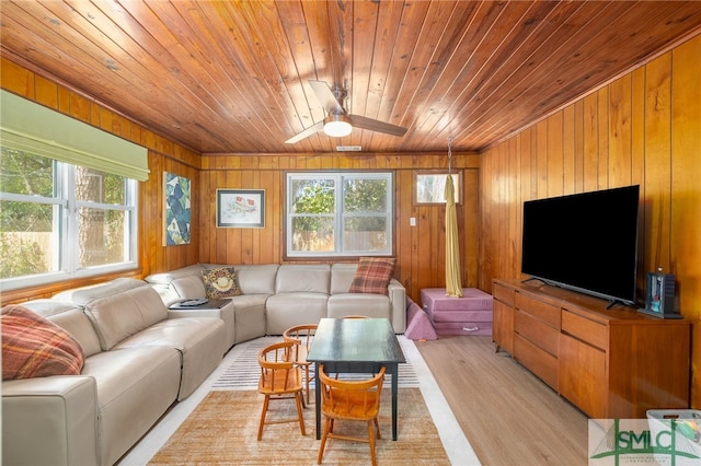 living room with wooden walls, light wood-style flooring, wood ceiling, and ceiling fan