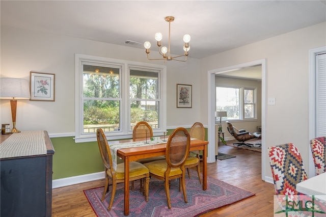 dining space with light wood finished floors, visible vents, baseboards, and an inviting chandelier