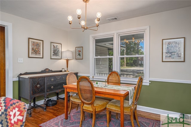 dining space featuring a notable chandelier, visible vents, baseboards, and wood finished floors