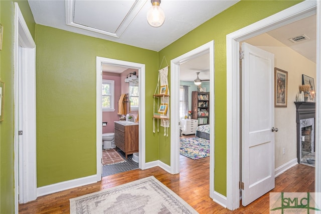 hallway with visible vents, baseboards, and wood finished floors