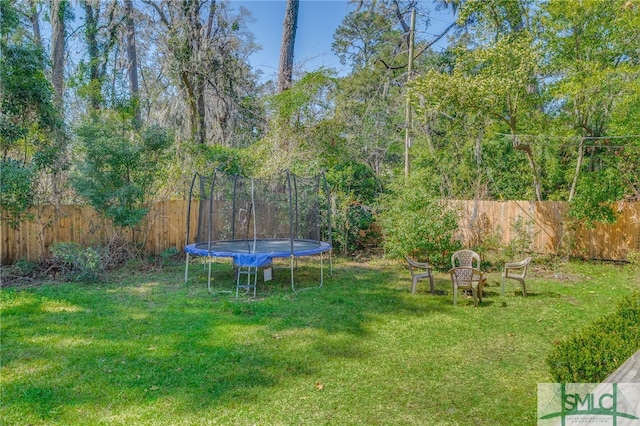 view of yard with a trampoline and fence