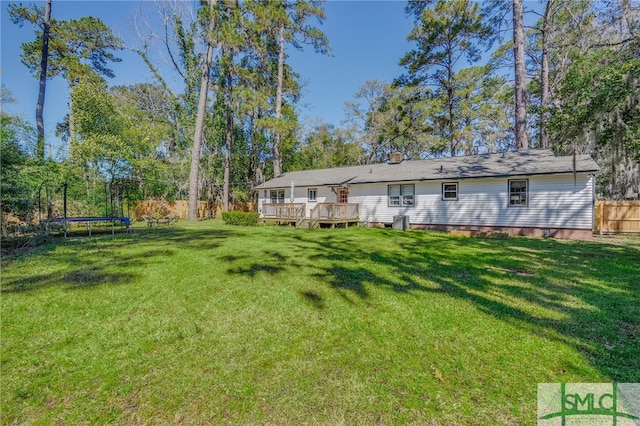 view of yard featuring cooling unit, a trampoline, a deck, and fence