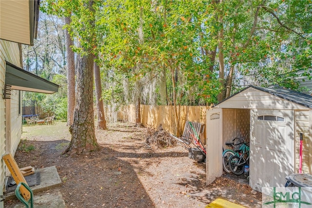 view of yard with an outbuilding, a trampoline, a fenced backyard, and a storage unit