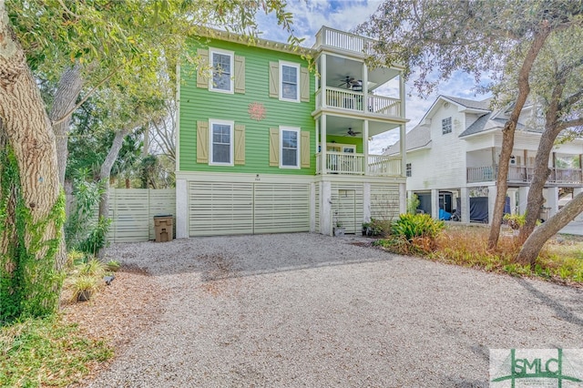 view of front of home featuring a garage, a balcony, gravel driveway, and ceiling fan