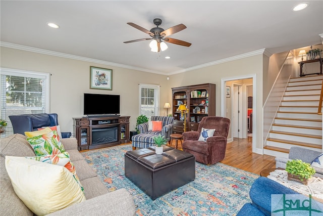 living room with stairway, wood finished floors, a ceiling fan, and ornamental molding