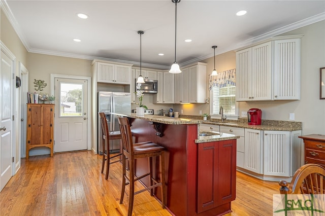 kitchen with stainless steel appliances, plenty of natural light, light wood-style floors, and crown molding