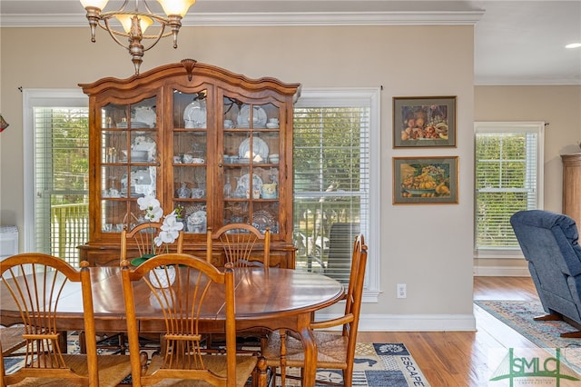 dining room featuring baseboards, light wood-type flooring, crown molding, and an inviting chandelier