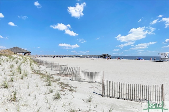 view of yard featuring fence, a beach view, and a water view