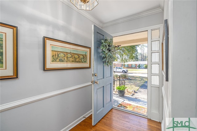 foyer entrance featuring crown molding, baseboards, and wood finished floors