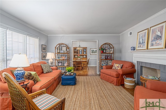 living area featuring visible vents, a fireplace, crown molding, and wood finished floors