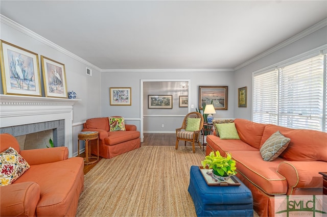 living area with visible vents, a brick fireplace, crown molding, and wood finished floors