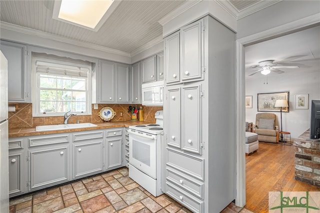 kitchen with gray cabinetry, a sink, white appliances, crown molding, and decorative backsplash