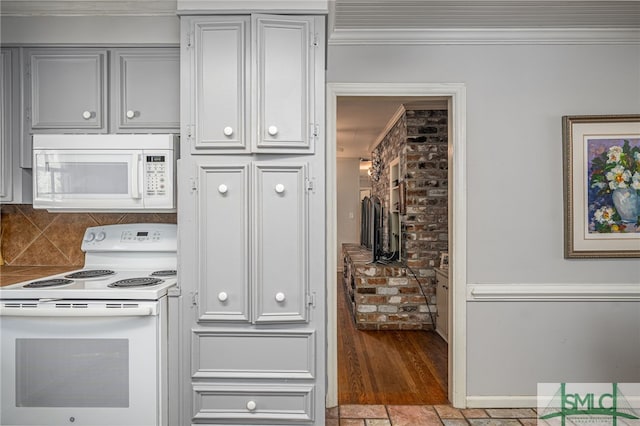 kitchen featuring brick wall, baseboards, ornamental molding, decorative backsplash, and white appliances