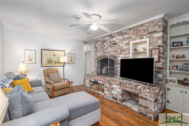 living room with wood finished floors, baseboards, a fireplace, ceiling fan, and ornamental molding