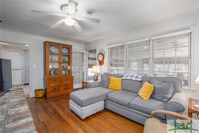 living area with wood finished floors, ceiling fan, and ornamental molding