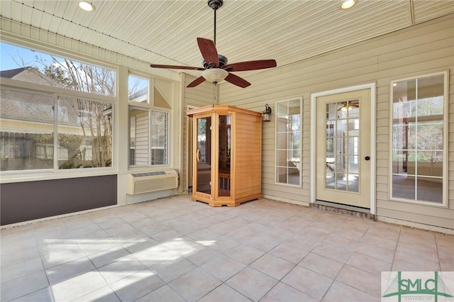 unfurnished sunroom with a ceiling fan and a wall unit AC