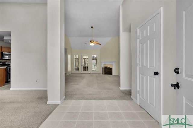 corridor with lofted ceiling, light tile patterned flooring, baseboards, and light carpet