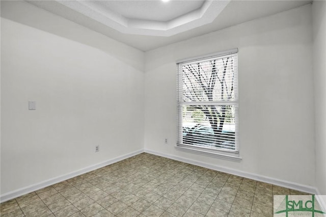 empty room with a tray ceiling and baseboards