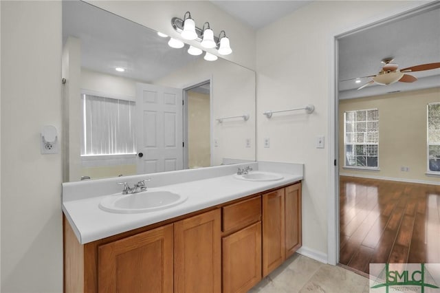 bathroom with double vanity, baseboards, a ceiling fan, and a sink