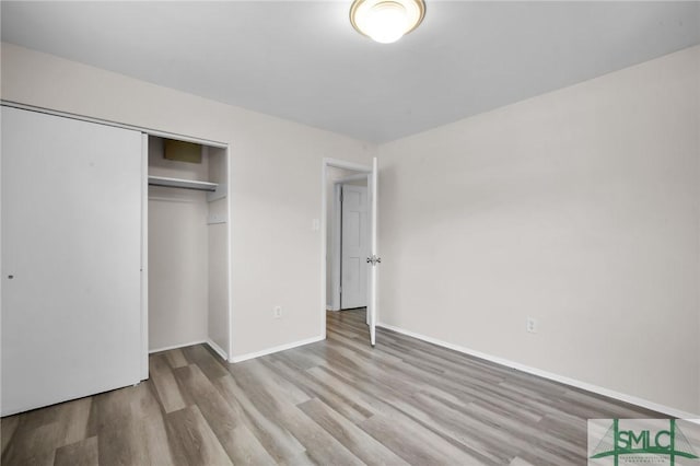 unfurnished bedroom featuring wood finished floors, a closet, and baseboards